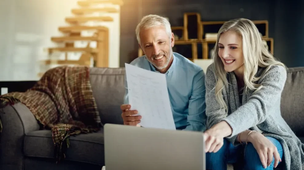 A smiling, mature couple reviews their finances, which are well handled thanks to wealth management services.